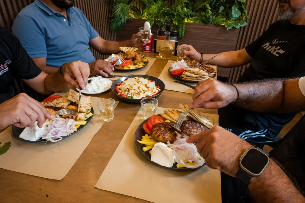 Παρέα τρώει μερίδες και πίτες γύρο στο τραπέζι του καταστήματος