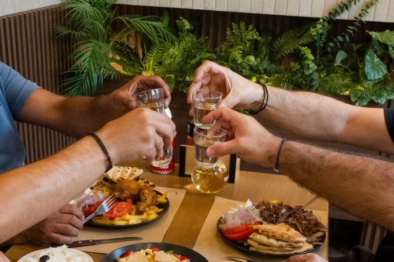 Παρέα τσουγκρίζει ποτήρια πάνω από τα πιάτα
