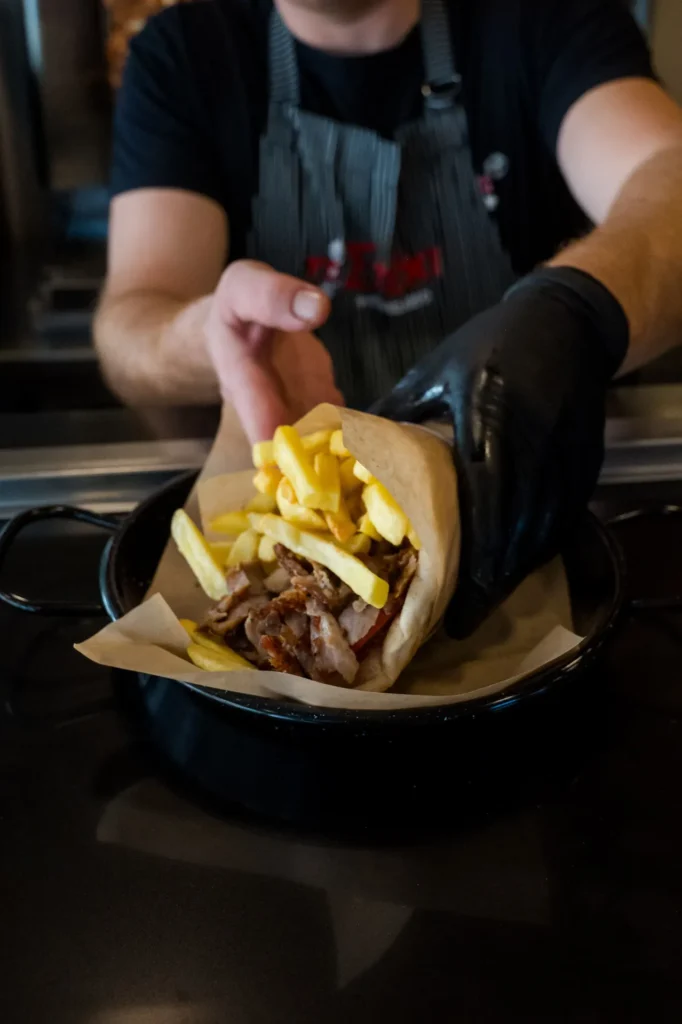 Τυλιγμένη πίτα γύρος με πατάτες δίνεται στο χέρι για take away
